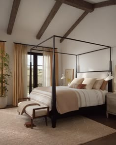 a bedroom with a four poster bed and beige curtains