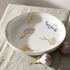 a bowl with flowers painted on it next to garlic