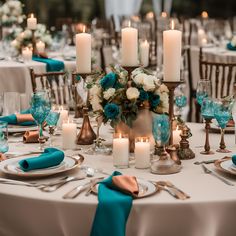 the table is set with blue and white flowers, silverware, candles, and napkins