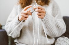 a woman sitting on top of a couch holding onto white string wrapped around her hands