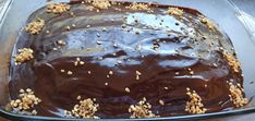 a chocolate cake with walnuts on top in a glass baking dish, ready to be eaten