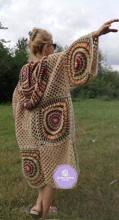 a woman in a crocheted shawl is holding out her hand to the sky