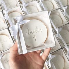 a hand holding up a white cookie in a box with the word and cross on it