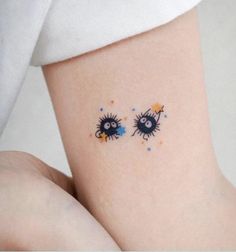 two small tattoos on the side of a woman's leg, one with blue eyes