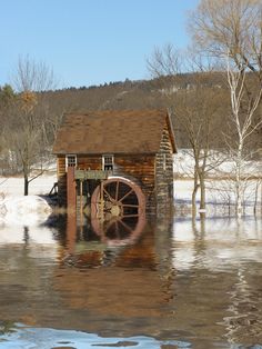 an old water mill sits in the middle of a flooded field with snow on the ground