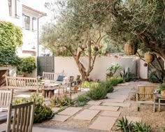 an outdoor patio with tables, chairs and trees in the back yard is surrounded by greenery