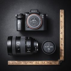 a camera, ruler and lens on a black surface