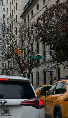 cars are stopped at an intersection in front of tall buildings and american flag on the corner