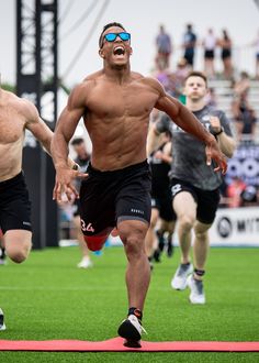 two men running on a field with one man wearing sunglasses and the other shirtless