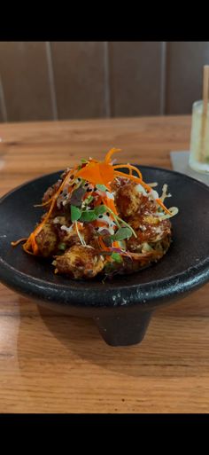 a black plate topped with food on top of a wooden table