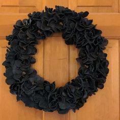 a black wreath is hanging on the front door and it looks like flowers are coming out