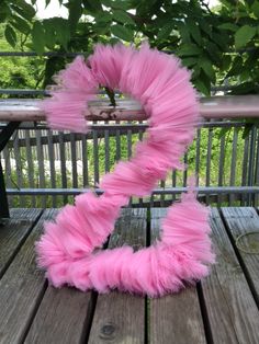 the letter z is made out of pink feathers on top of a wooden table with a tree in the background