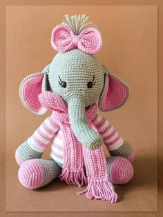 a crocheted stuffed elephant with a pink and white scarf on it's head