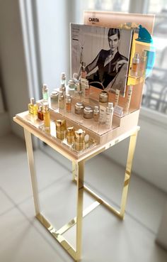 a table with bottles on it in front of a window and an image of a woman