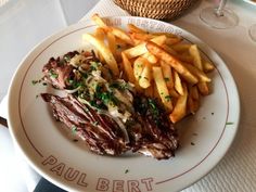 a steak and french fries on a white plate