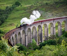 a train traveling over a bridge with steam pouring out of it