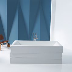 a white bath tub sitting next to a wooden chair in a room with blue walls