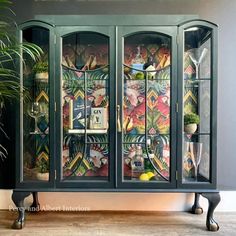 an old china cabinet is decorated with colorful wallpapers and glass doors, as well as potted plants