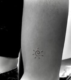 a woman with a small sun tattoo on her left side ribcading the arm