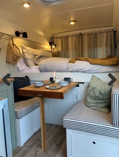 the interior of a camper with two beds and a table in front of it