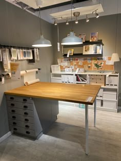 an office desk with drawers and hanging lights