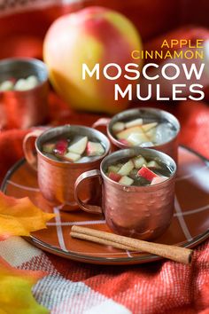 apple cinnamon moscow mules are served in copper mugs on a plaid tablecloth