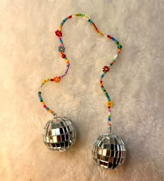 two disco ball ornaments on a white furnishing with beaded necklaces and beads