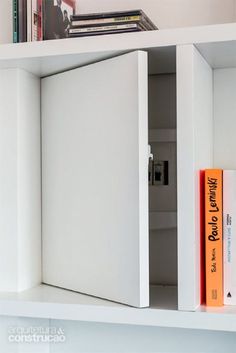 an open book shelf with books on it and a white cabinet in the corner behind it