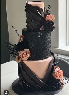 a three tiered black and pink cake with flowers