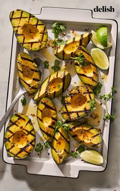 grilled avocados with limes and cilantro on a white platter