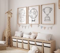 a child's room with three framed pictures on the wall and two stuffed giraffes