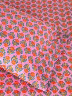 an orange and pink flowered pattern on a bed sheet that has been made into a pillow