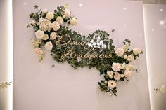 flowers and greenery are arranged on the wall in front of an advertise