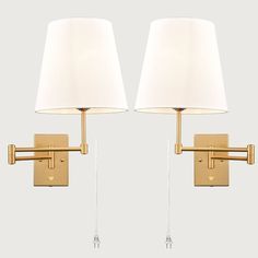 two wall lamps with white shades on them