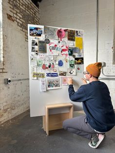 a man sitting on the ground in front of a whiteboard covered with stickers