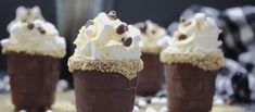 four ice cream cones topped with chocolate and marshmallows are on a table