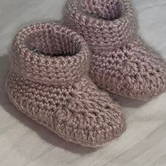 a pair of crocheted slippers sitting on top of a bed