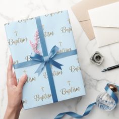 a person holding a wrapped gift box with blue ribbon on it, surrounded by other items