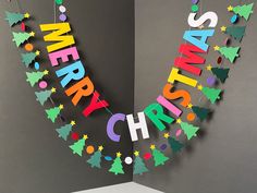 a christmas card with the word merry written in multicolored letters and trees on it