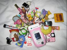 an assortment of various items on a white sheet, including a cell phone and keychain