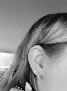 black and white photograph of a woman with ear piercings on her ears, looking out the window