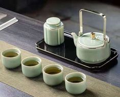 four cups and a tea pot on a tray