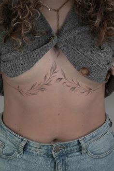 a woman's stomach with tattoos on her chest and bottom part showing leaves in the middle