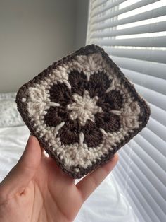 someone is holding up a crocheted square in their hand, with the flower on it