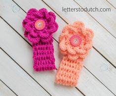 two crocheted flower headbands sitting next to each other on a wooden surface