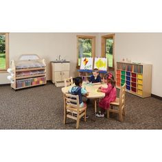 two children sitting at a table in a playroom