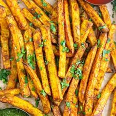 baked french fries with parsley on top and dipping sauce in small bowls next to them