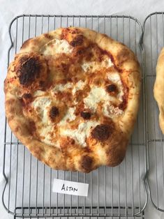 two pizzas sitting on top of cooling racks next to each other