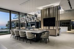 a large dining room table surrounded by beige chairs and an open floor plan with glass doors leading to the ocean