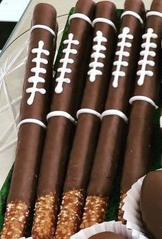 chocolate footballs and pretzels are arranged on a platter with paper wrappers